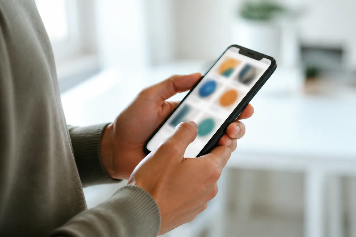 Mains tenant un smartphone montrant une page de boutique en ligne aux formes colorées