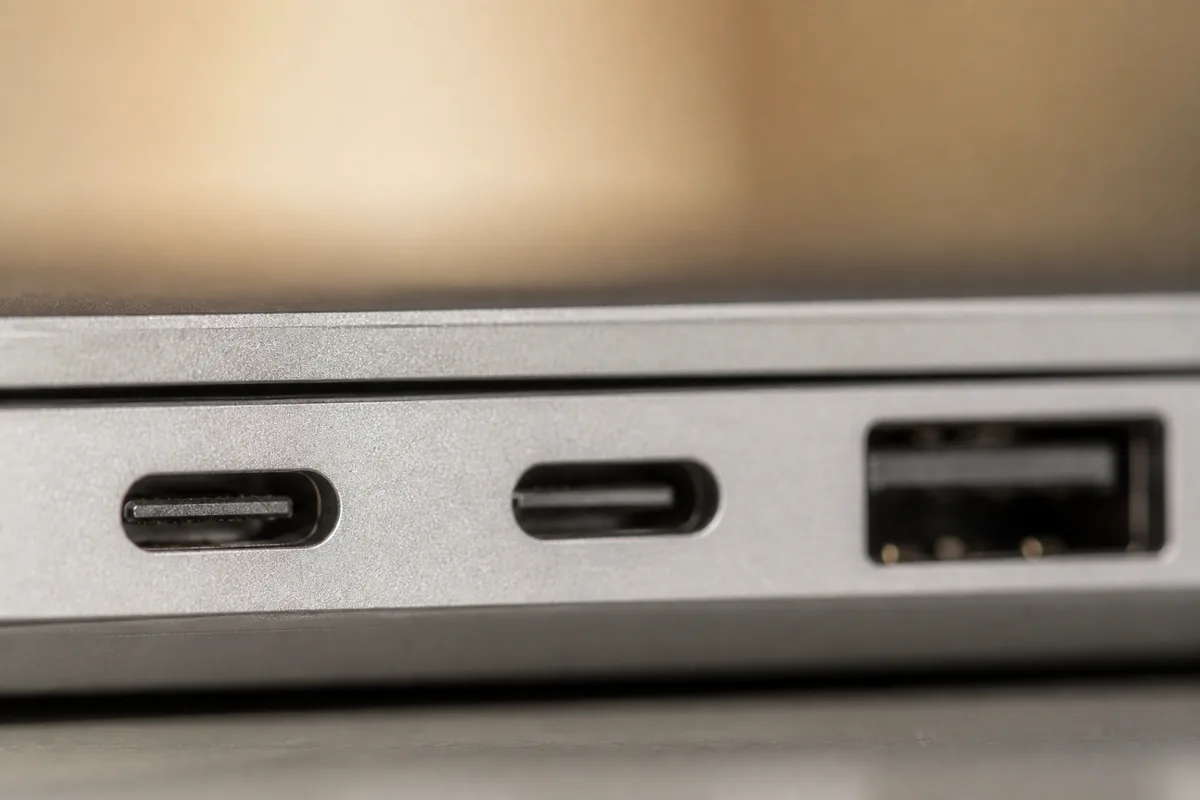 Gros plan sur une rangée de ports USB-C et USB-A au flanc d&rsquo;un ordinateur portable, lumière naturelle rasante